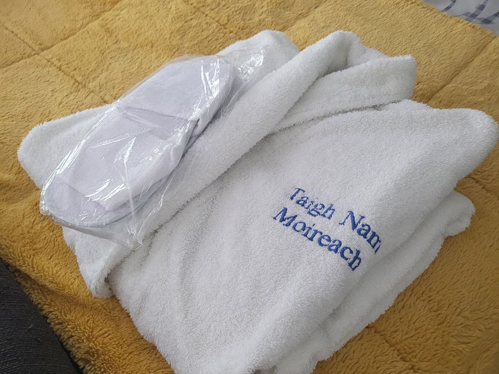 A bathrobe and slippers on a bed at Taigh Nam Moireach in Inverness