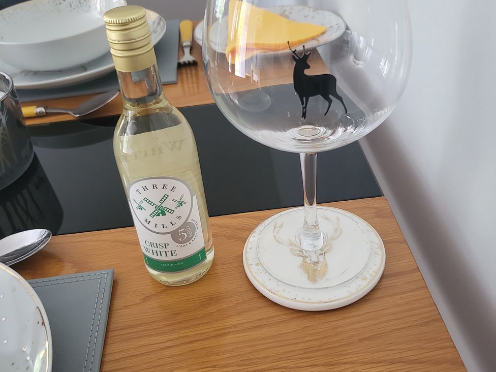 A bottle of wine and a glass on a dining table at Taigh Nam Moireach in Inverness