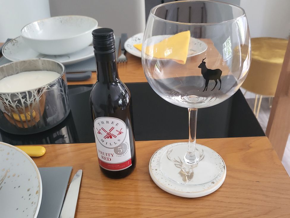 A bottle of wine and a glass on a dining table at Taigh Nam Moireach in Inverness