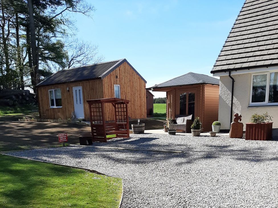 An outdoor setting with a wooden cabin and garden shed at Taigh Nam Moireach in Inverness