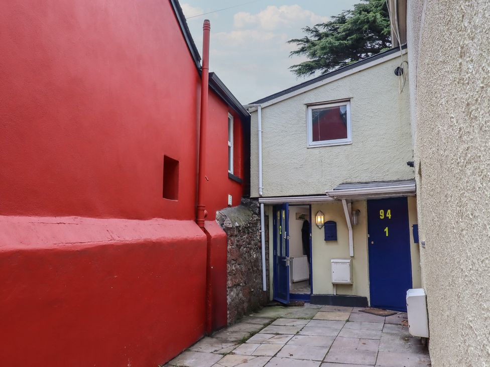 An alleyway with red and white walls and blue doors at Teign Place in Teignmouth