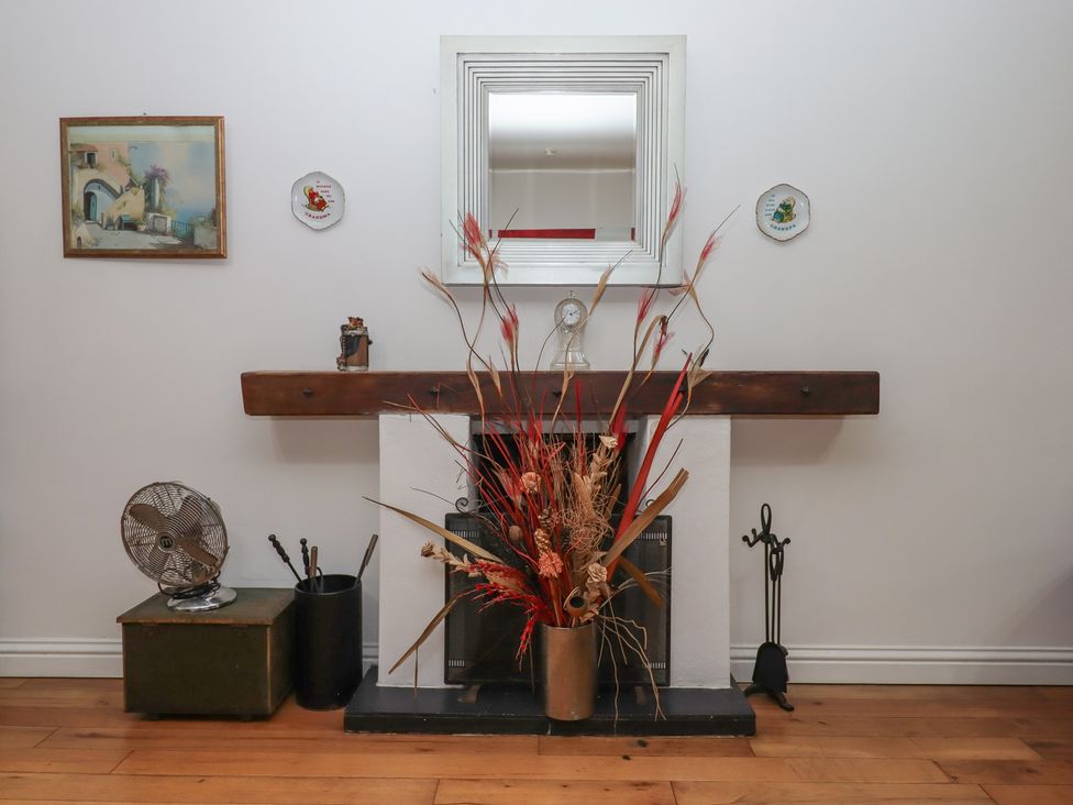 A fireplace with a mirror and flower arrangement at Teign Place in Teignmouth