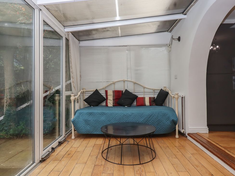 A conservatory with a daybed and coffee table at Teign Place in Teignmouth
