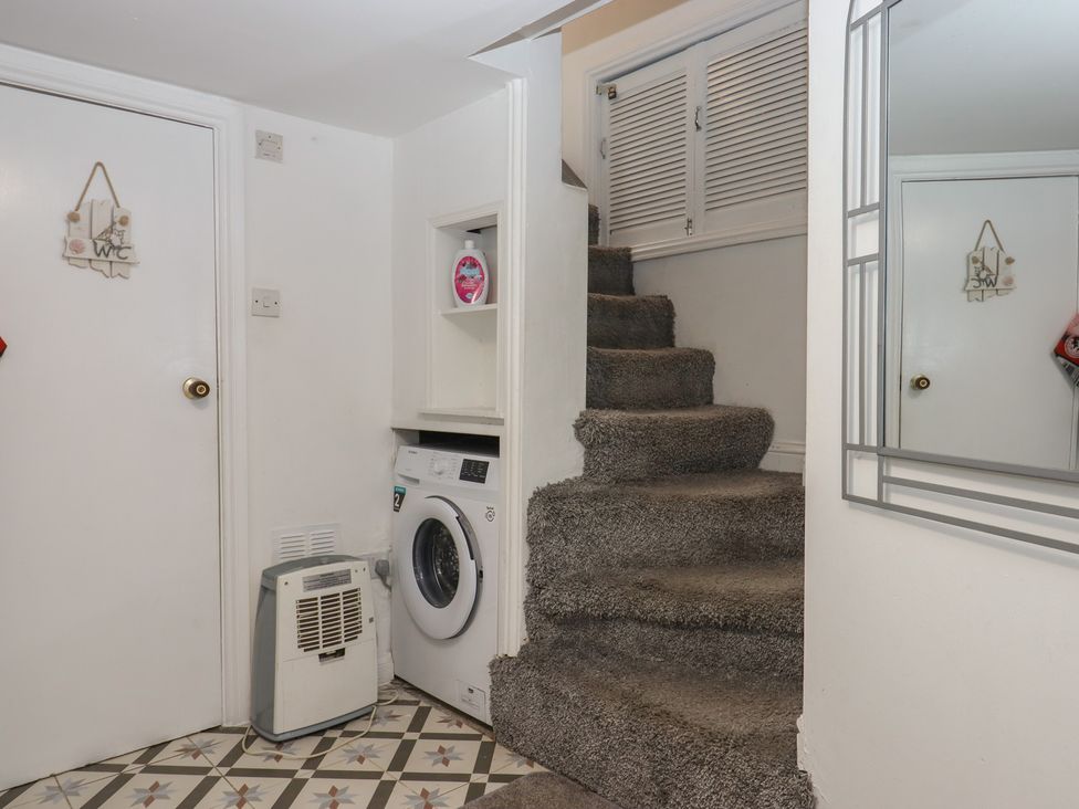 A hallway with a washing machine and staircase at Teign Place in Teignmouth