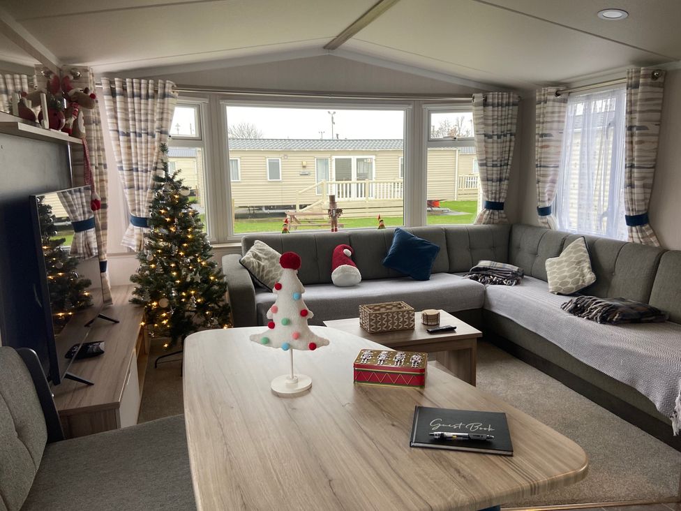 A living room with a sofa and a tree at Elms 32 in Porthcawl
