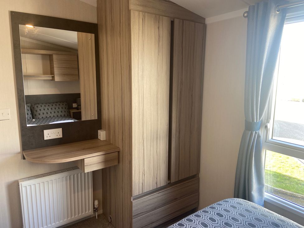 A bedroom with a wardrobe and table at Elms 32 Porthcawl