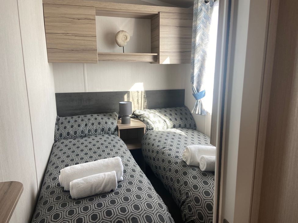 A bedroom with twin beds and a shelf at Elms 32 in Porthcawl