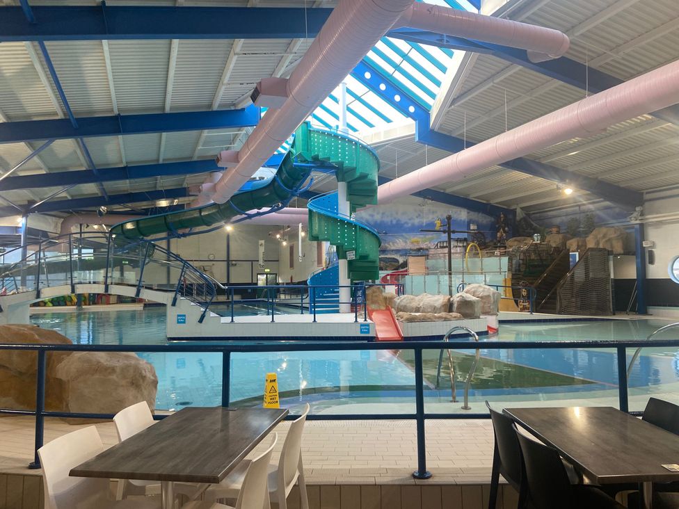 An indoor pool area with a water slide and seating at Elms 32 in Porthcawl