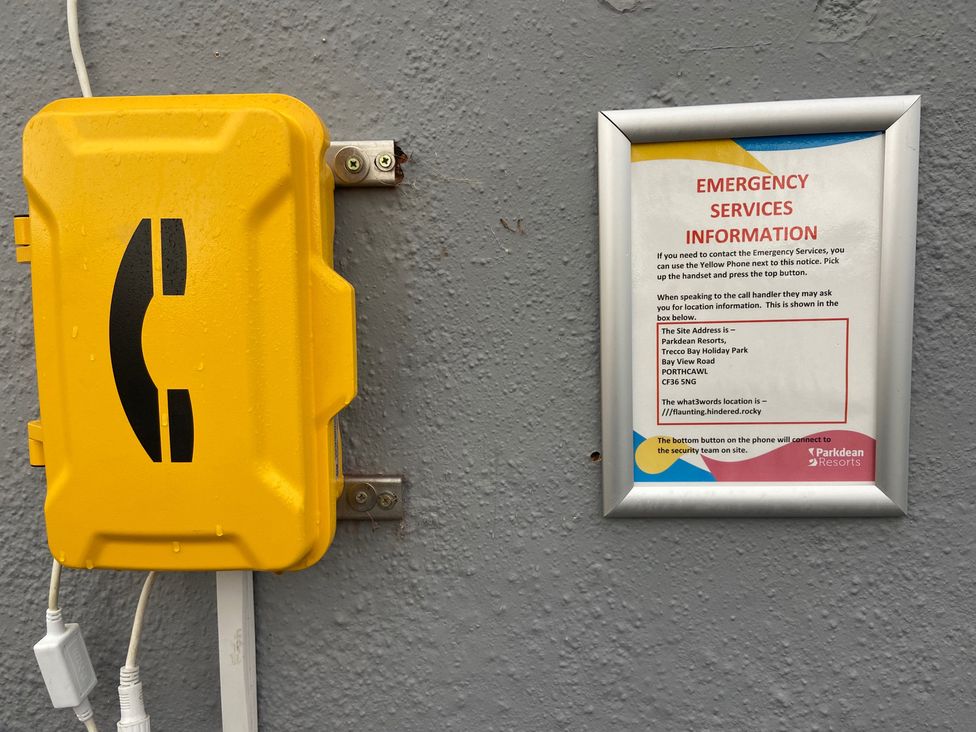 A yellow phone box and emergency services information sign at Parkdean Resorts in Porthcawl