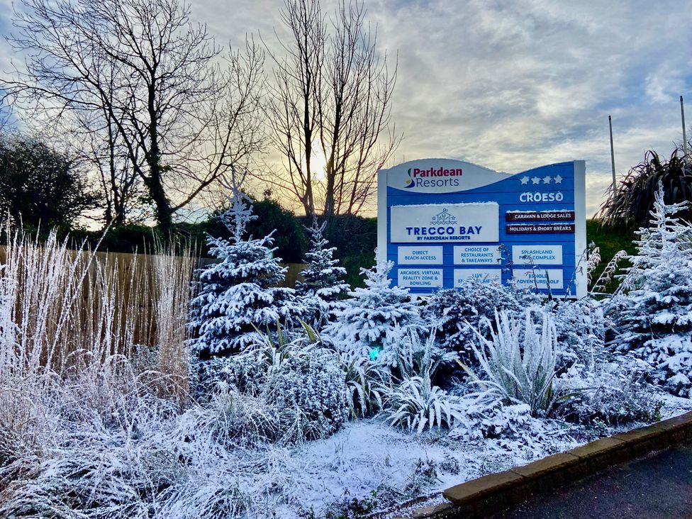 A sign for Trecco Bay at Parkdean Resorts with snowy trees in Porthcawl