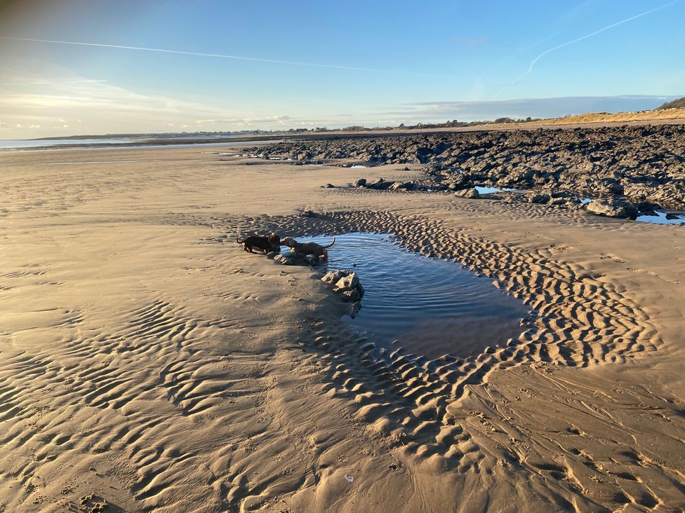 A beach with water puddles and rocks at Elms 32 in Porthcawl