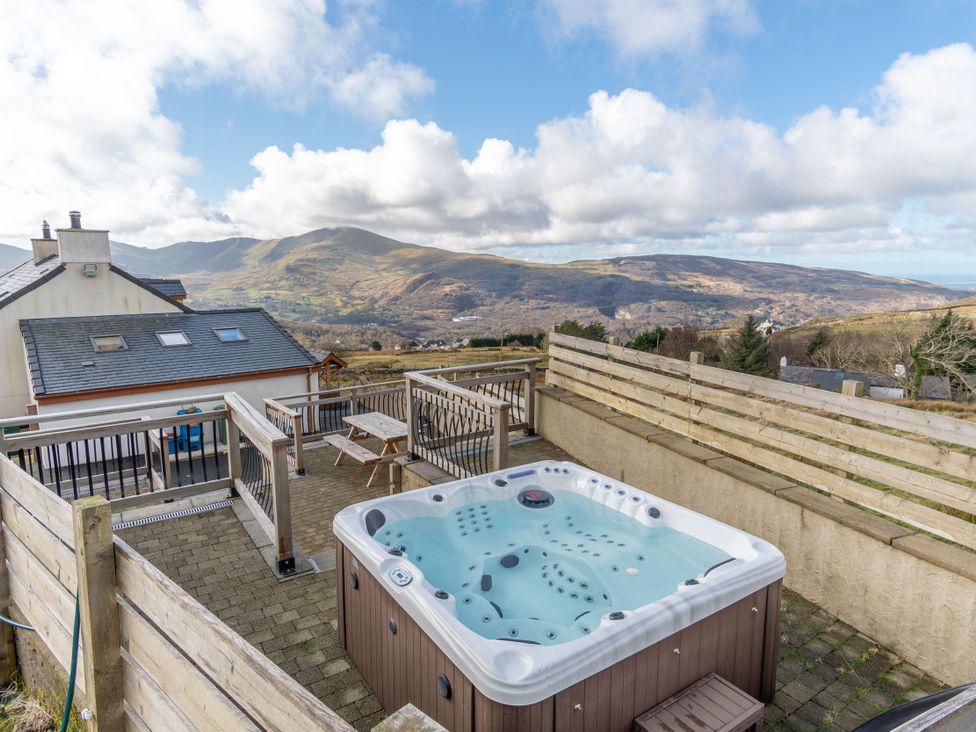 An outdoor area with a hot tub and table at Groeslon Uchaf in Caernarfon