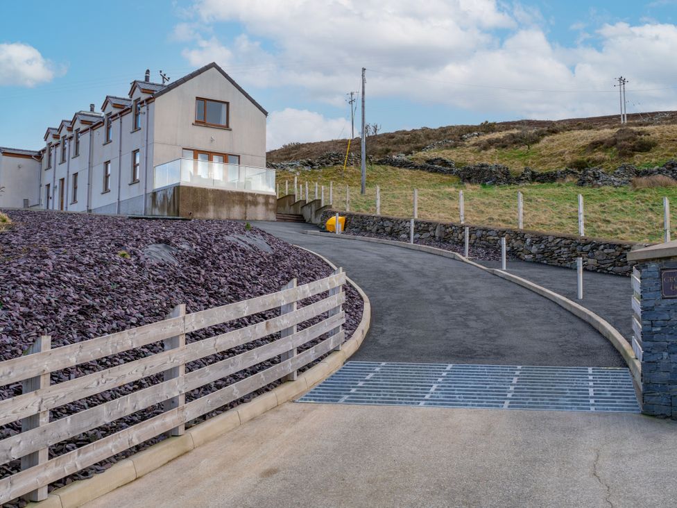 A house with a driveway and fence at Groeslon Uchaf in Caernarfon