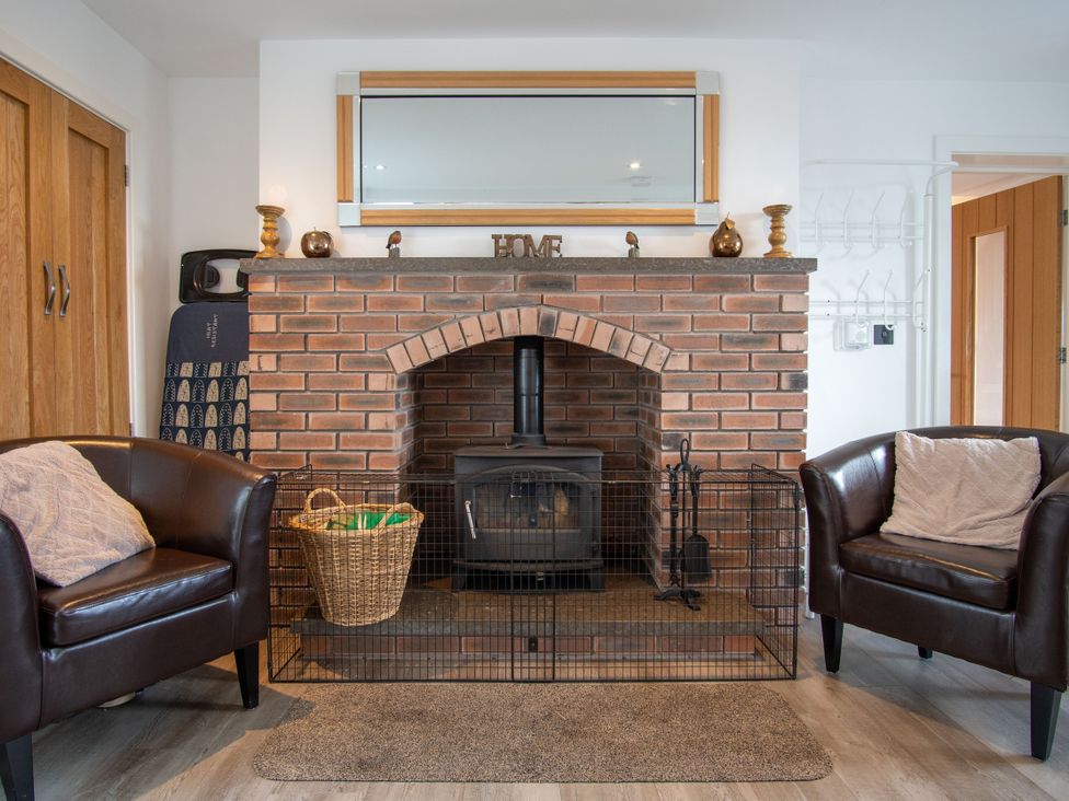 A living room with a fireplace and chairs at Groeslon Uchaf in Caernarfon