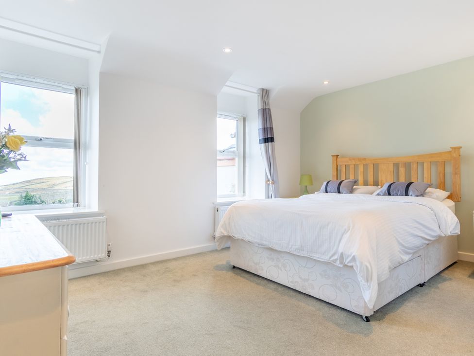 A bedroom with a bed and windows at Groeslon Uchaf in Caernarfon