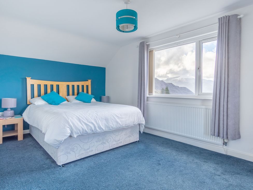 A bedroom with a bed and window at Groeslon Uchaf in Caernarfon