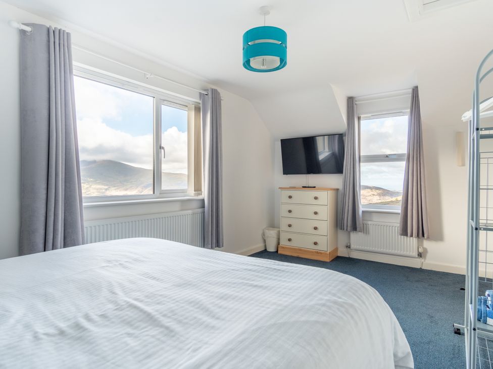 A bedroom with a bed and television at Groeslon Uchaf in Caernarfon