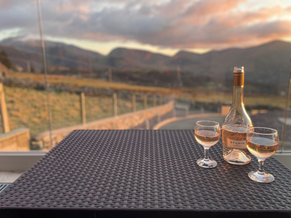 A table with a bottle and glasses overlooking mountains at Groeslon Uchaf Caernarfon
