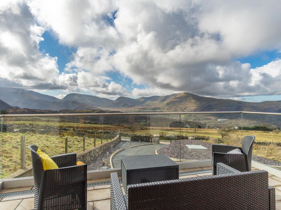An outdoor seating area with furniture overlooking mountains at Groeslon Uchaf in Caernarfon
