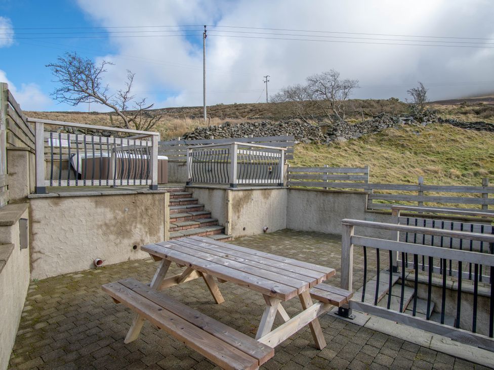 An outdoor area with a table and benches at Groeslon Uchaf in Caernarfon