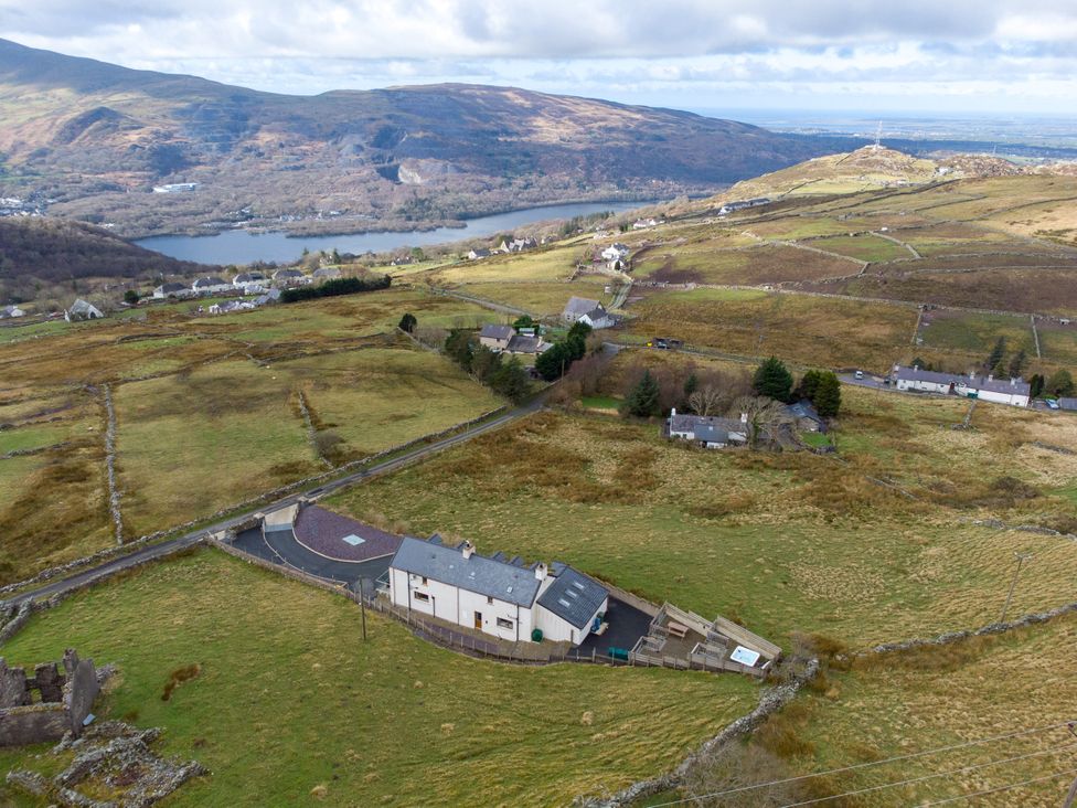 An aerial view of houses and fields near a lake at Groeslon Uchaf in Caernarfon