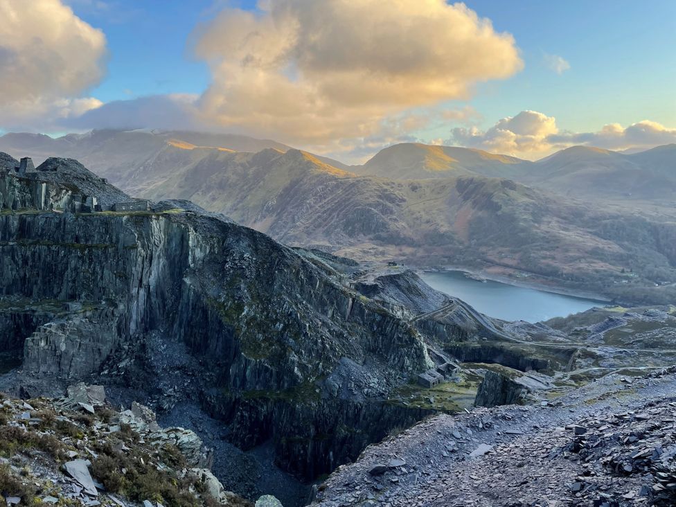 A landscape view of a quarry and lake with mountains in the background at Groeslon Uchaf Caernarfon