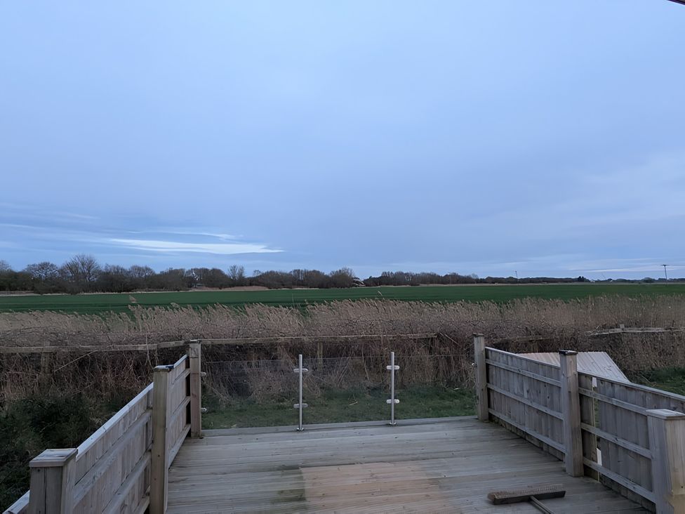 An outdoor area with a wooden deck overlooking a field at Lighthouse Lodge in Mablethorpe