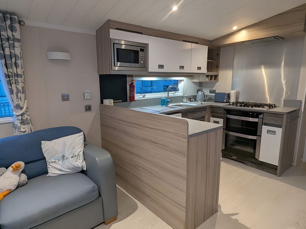 A kitchen with a sofa and cooking appliances at Lighthouse Lodge in Mablethorpe