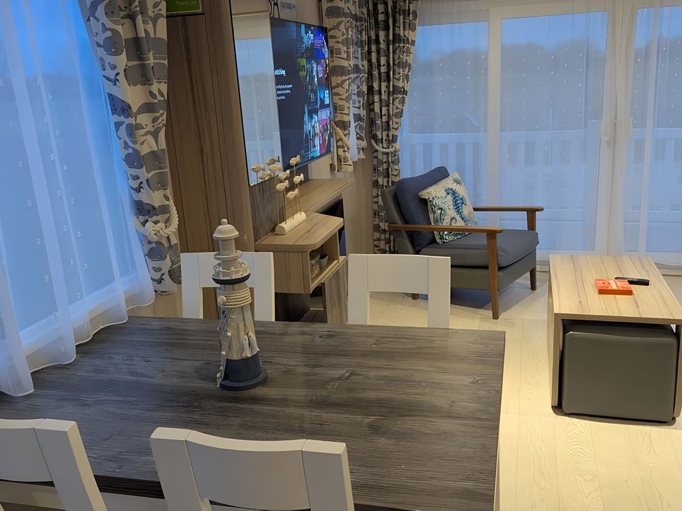 A living room with a dining table and an armchair at Lighthouse Lodge in Mablethorpe