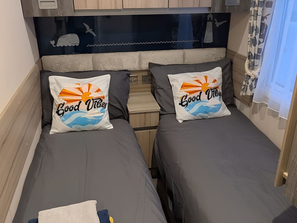 A bedroom with two single beds and decorative pillows at Lighthouse Lodge in Mablethorpe