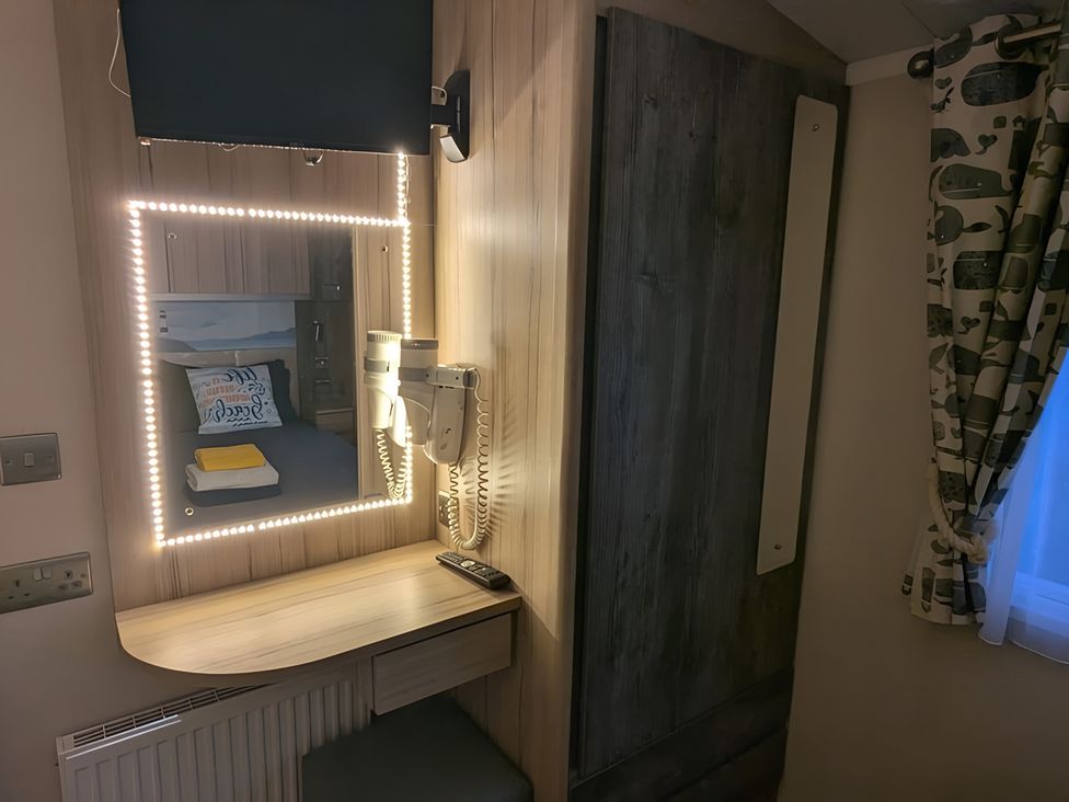 A bedroom with a TV, mirror, and telephone at Lighthouse Lodge in Mablethorpe