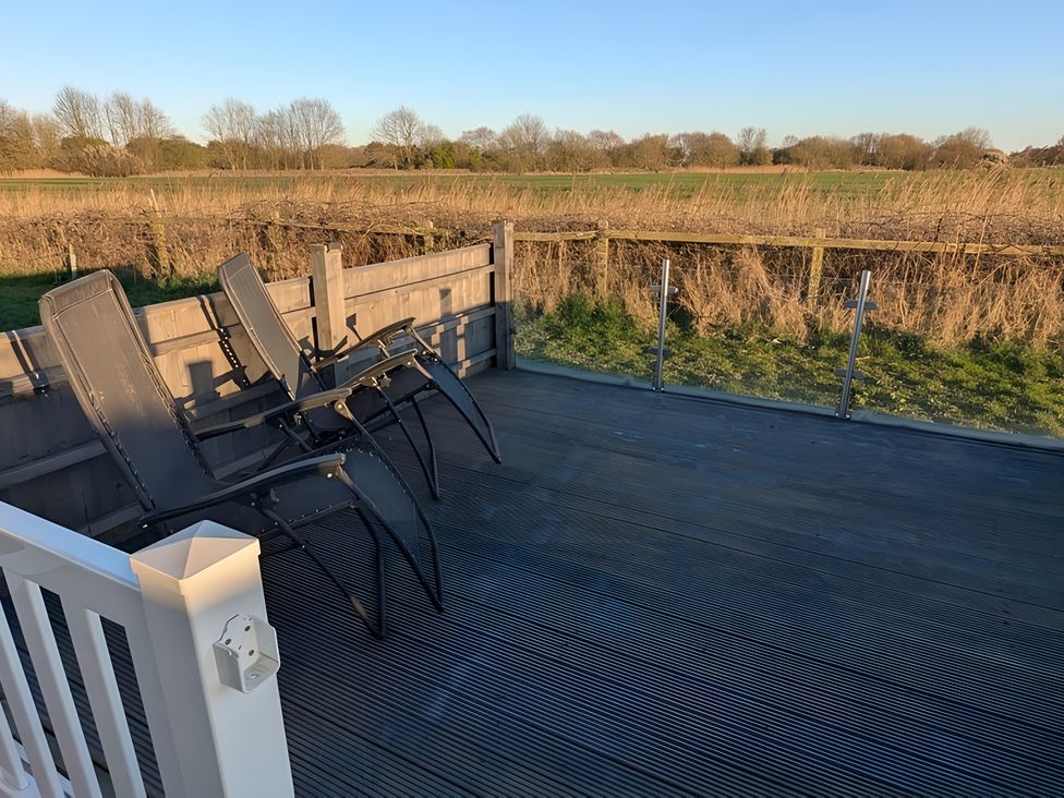 An outdoor area with chairs on a deck at Lighthouse Lodge in Mablethorpe