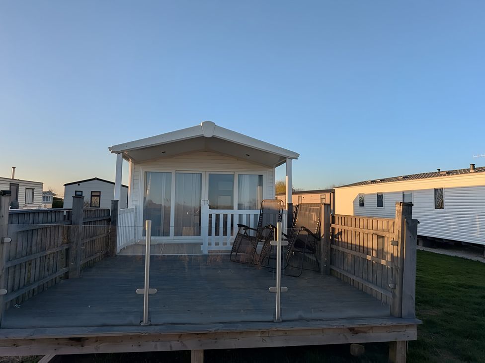A deck with chairs in front of a house at Lighthouse Lodge in Mablethorpe