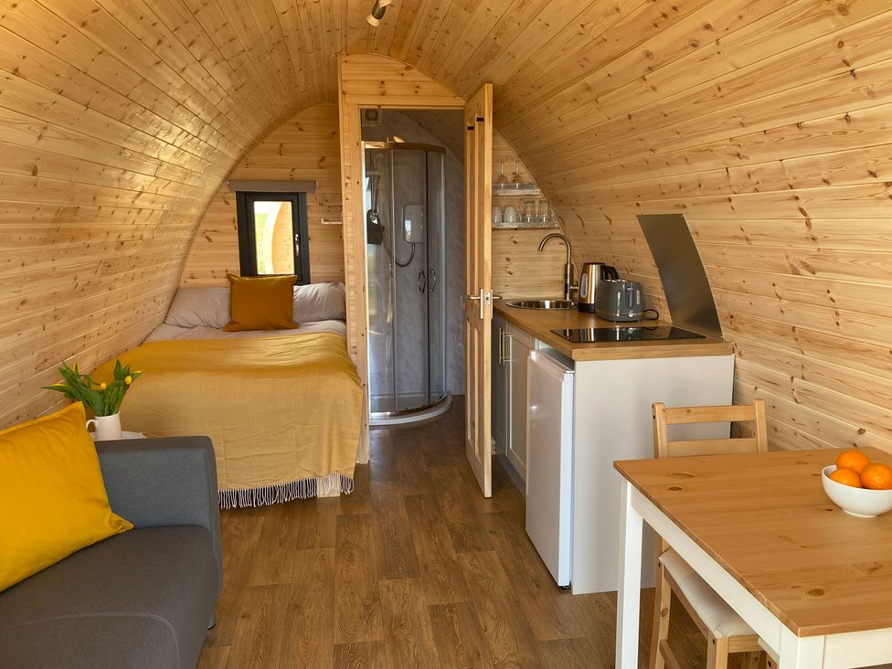 A sleeping area with a sofa and kitchenette at Kirkapol Beach Pod - Flow Isle of Tiree