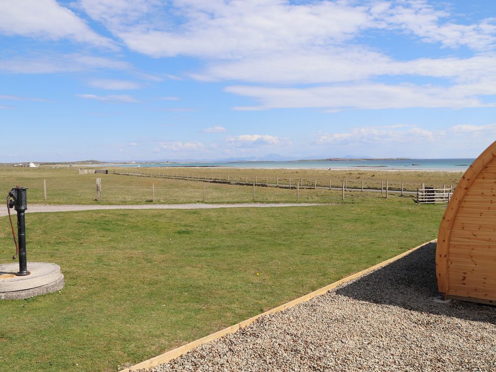 An outdoor area with grass and a wooden structure at Kirkapol Beach Pod - Flow Isle of Tiree