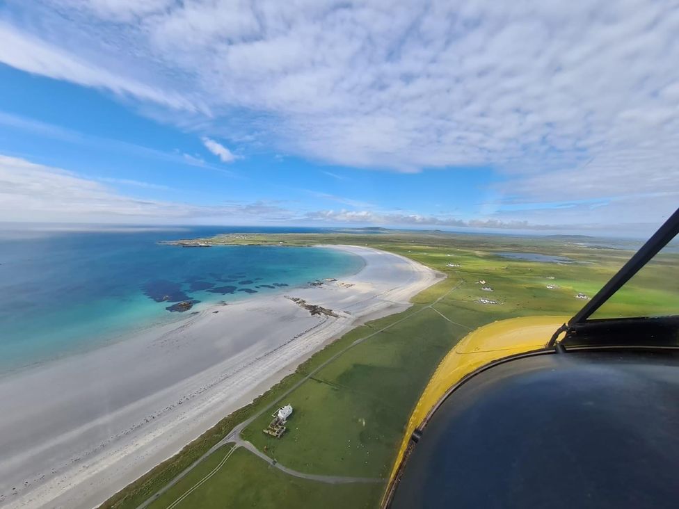 An aerial view of a beach and green land at Kirkapol Beach Pod - Flow Isle of Tiree