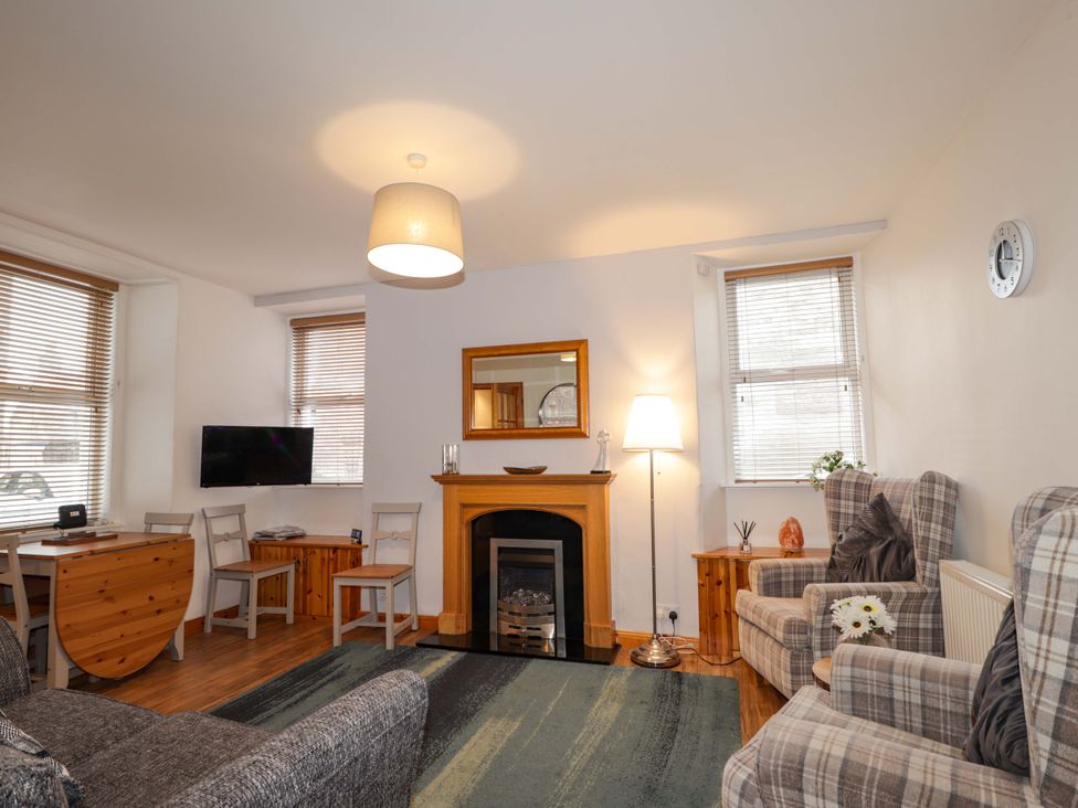 A living room with a fireplace and seating area at 1 Roseneath Terrace Nairn