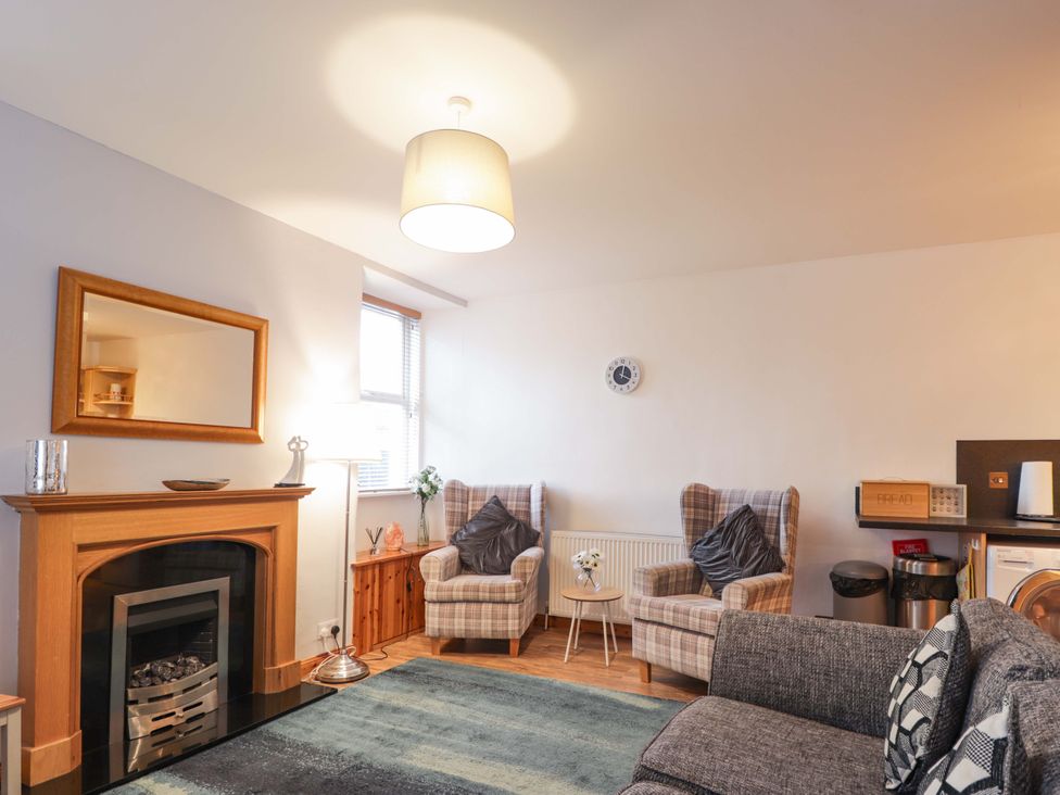 A living room with a fireplace and two armchairs at 1 Roseneath Terrace Nairn