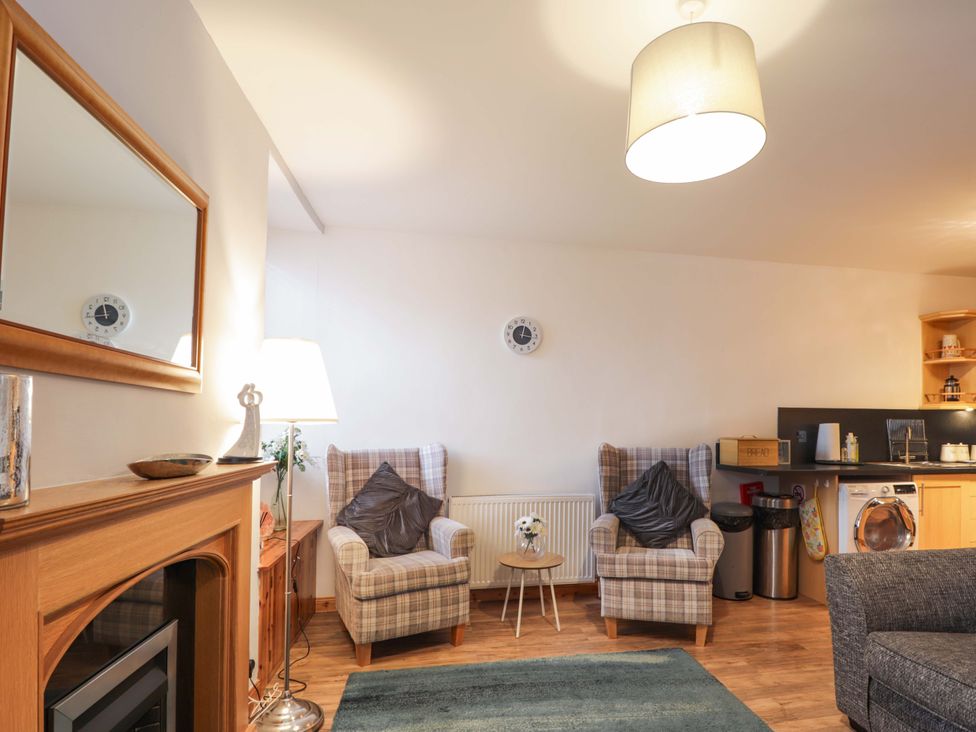 A living room with two armchairs and kitchen area at 1 Roseneath Terrace Nairn