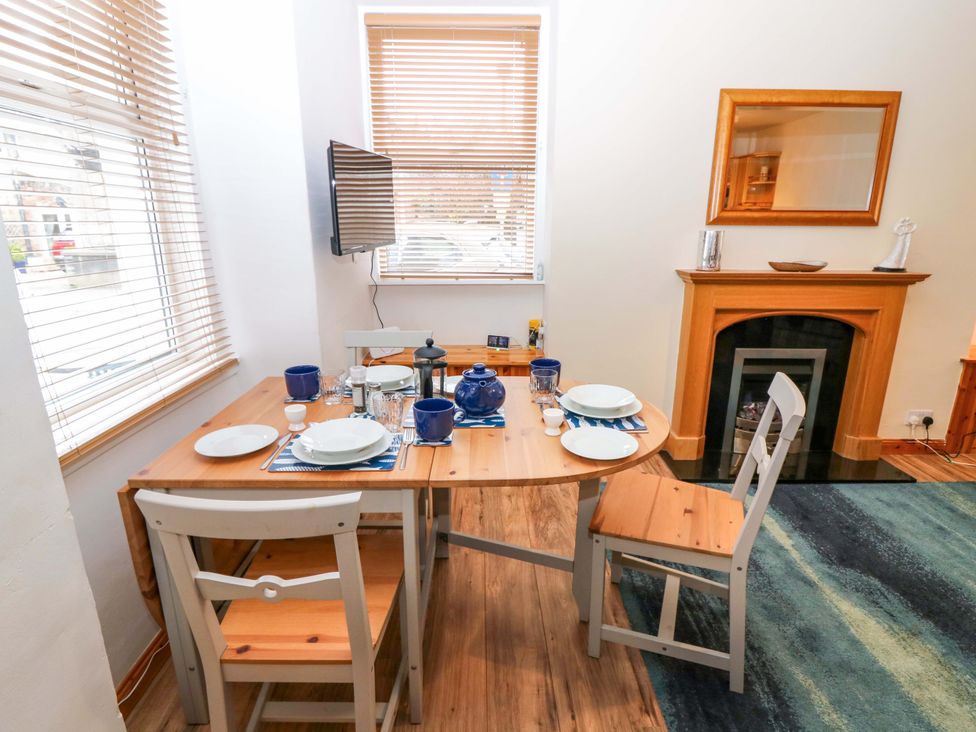 A dining room with a table set for meals at Rose Cottage Nairn