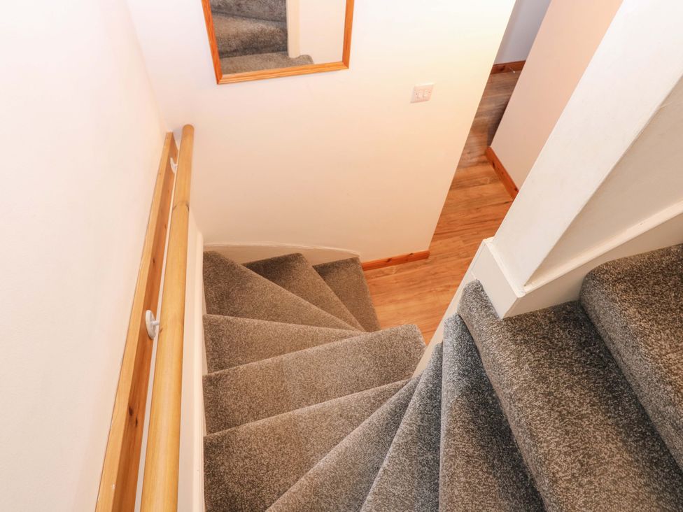 A staircase with a handrail and mirror at Rose Cottage Nairn