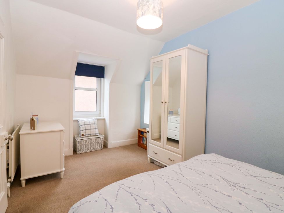 A bedroom with a bed and wardrobe at Rose Cottage in Nairn