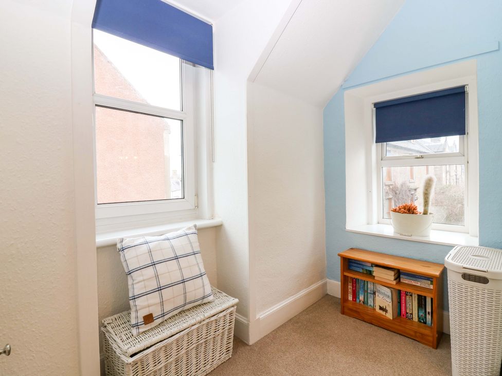 A room with a window, storage box, and bookshelf at Rose Cottage in Nairn