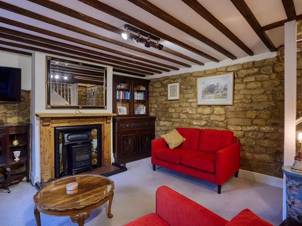 A living room with a red sofa and fireplace at Evas Cottage in Southam