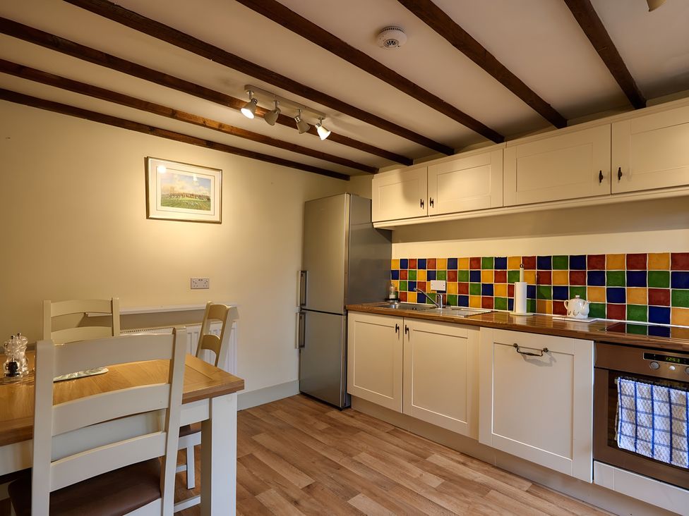 A kitchen with wooden beams and colorful tiles at Evas Cottage in Southam