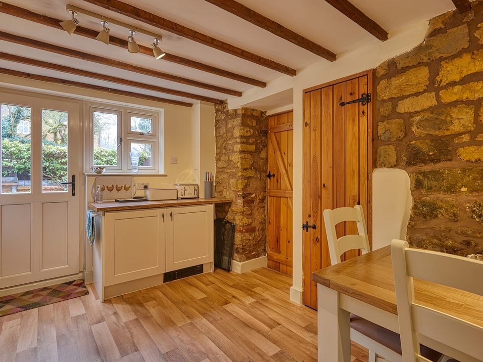 A kitchen with cabinets and a table at Evas Cottage in Southam