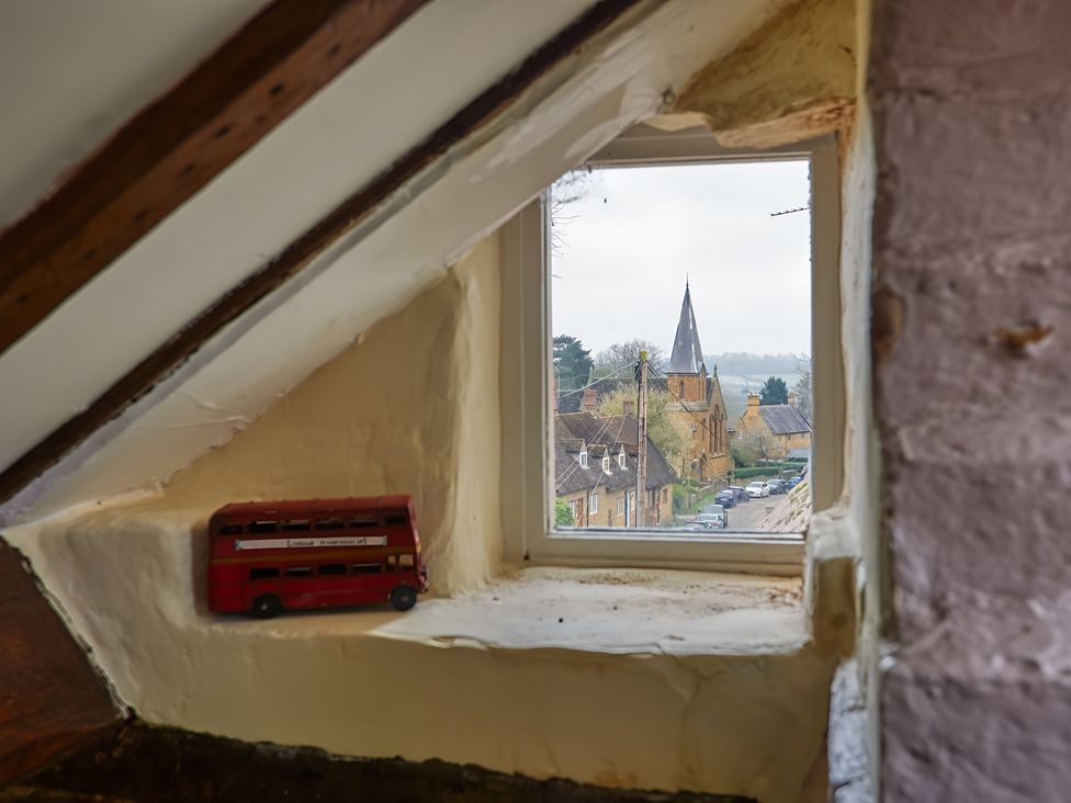 A window view of a church and street from the attic at Evas Cottage in Southam