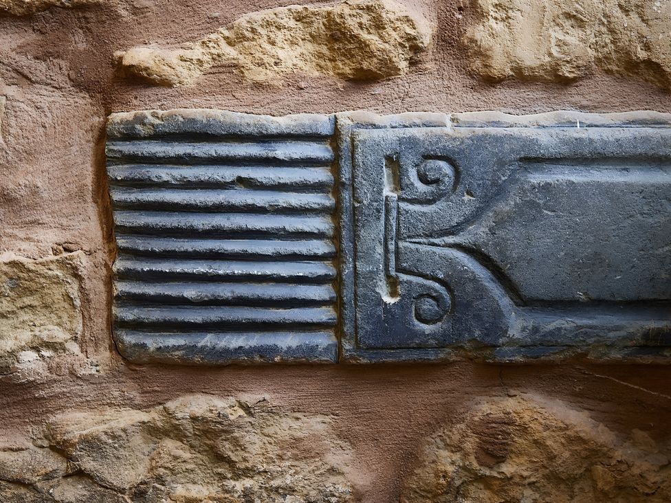A stone wall with an ornamental panel and grooves at Evas Cottage Southam