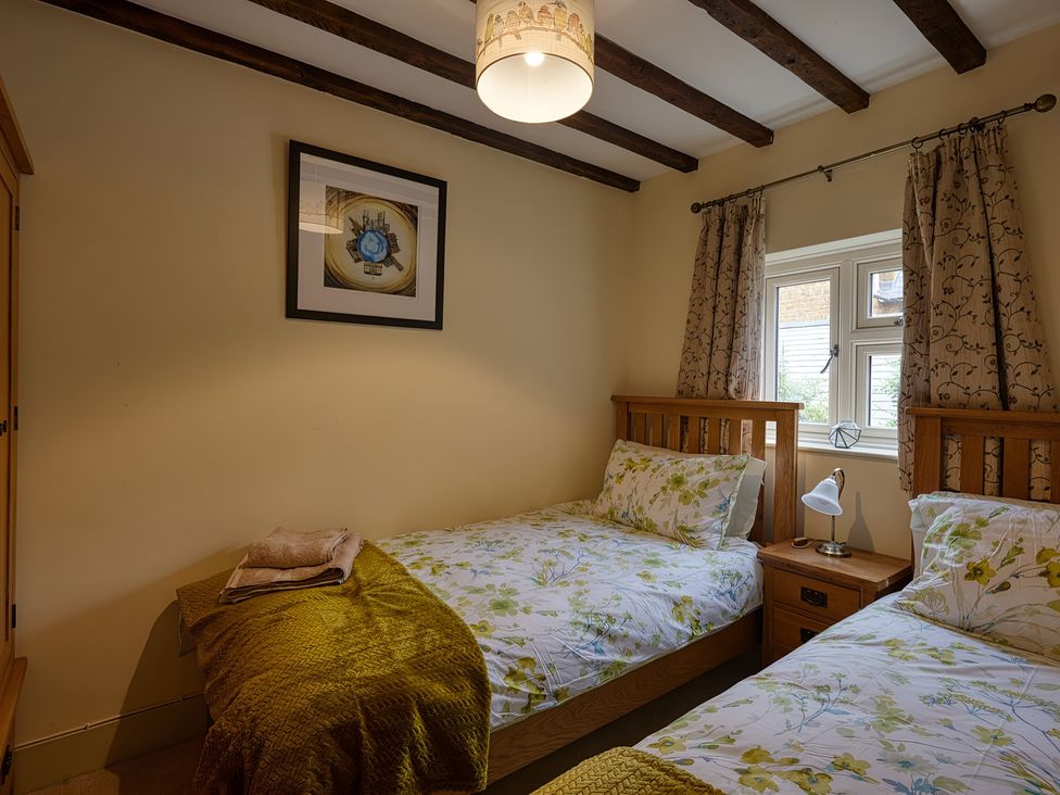A bedroom with two beds and a window at Evas Cottage in Southam