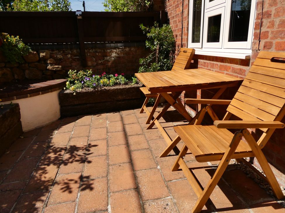 A garden with wooden furniture and flowers at Evas Cottage in Southam